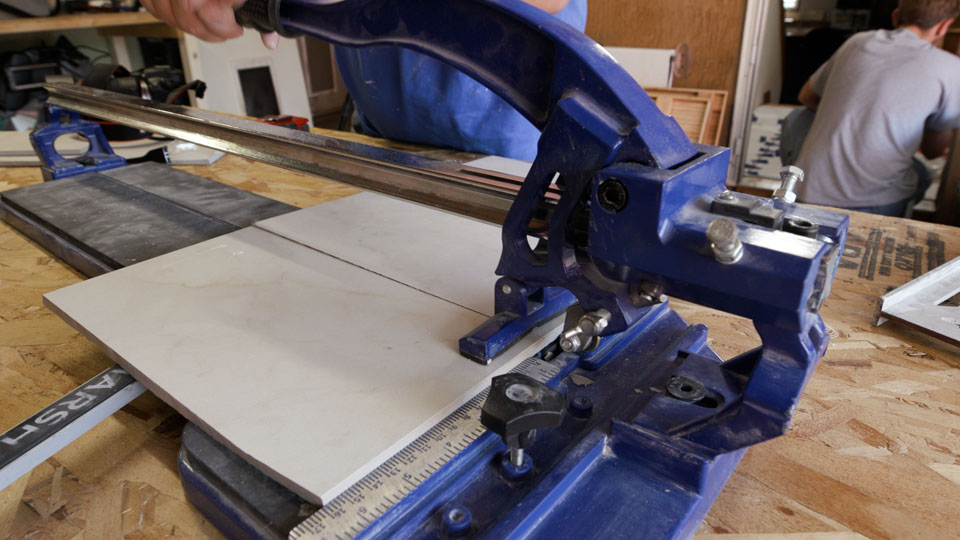 Engaging the breaker foot on the tile cutter to snap the tile